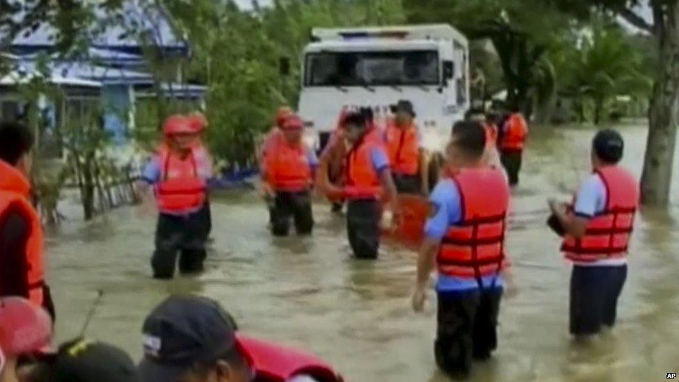 Rescuers wade through flood waters caused by Typhoon Haiyan in Mindoro, Philippines