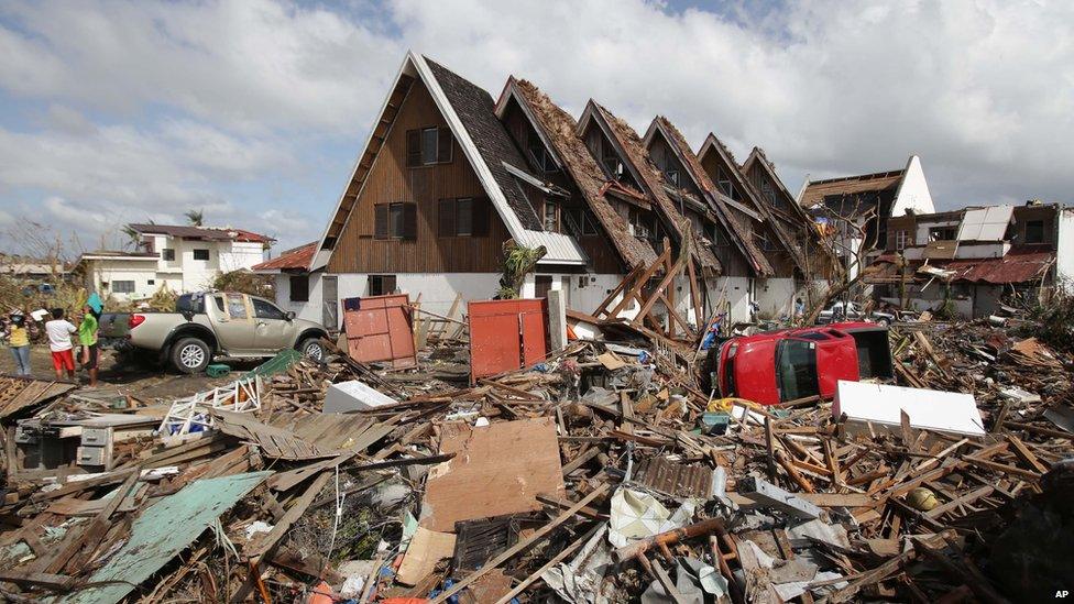 Survivors stand outside their damaged house at typhoon-hit Tacloban city, Leyte province central Philippines on 11 November 2013