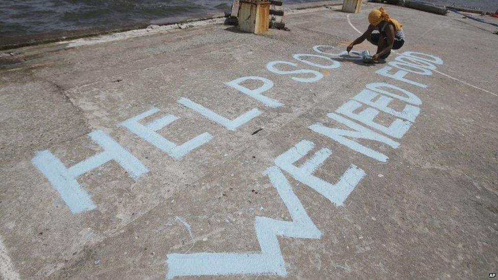 A survivor writes a message on their port to call for help at typhoon-ravaged Tacloban city, Leyte province, 11 November 2013