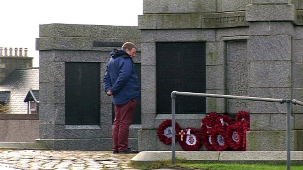 Man stands in front of a war memorial