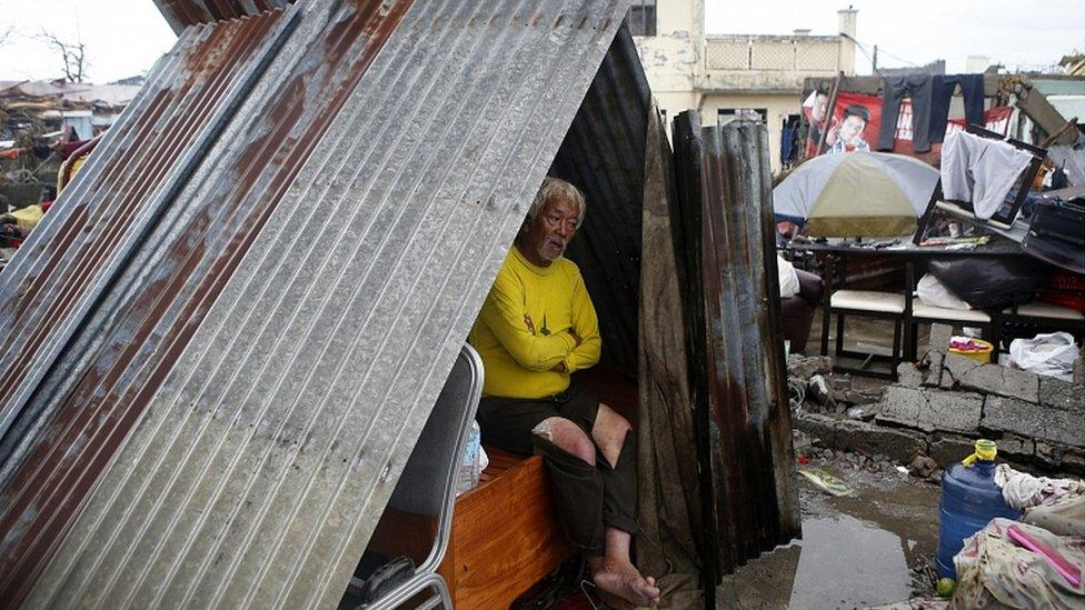 A man made homeless by Typhoon Haiyan sits at a makeshift shelter along a road in Palo, Leyte