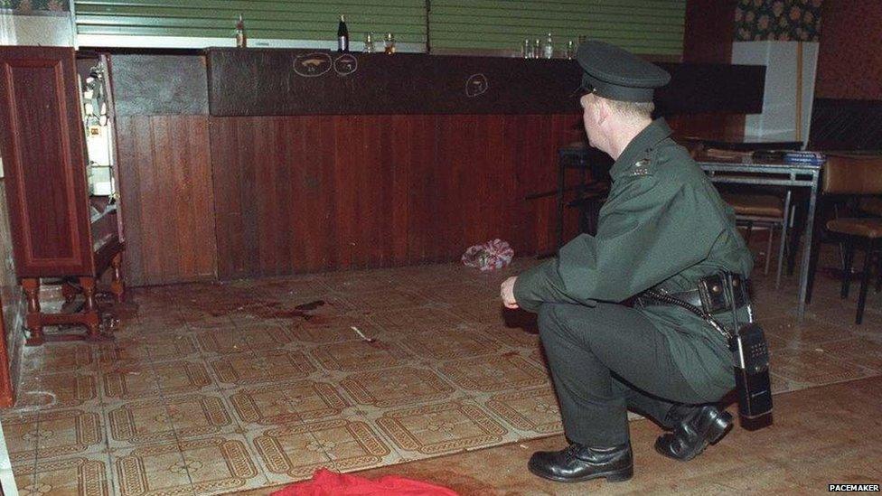 An officer sits and looks at the bloodied floor of the bar