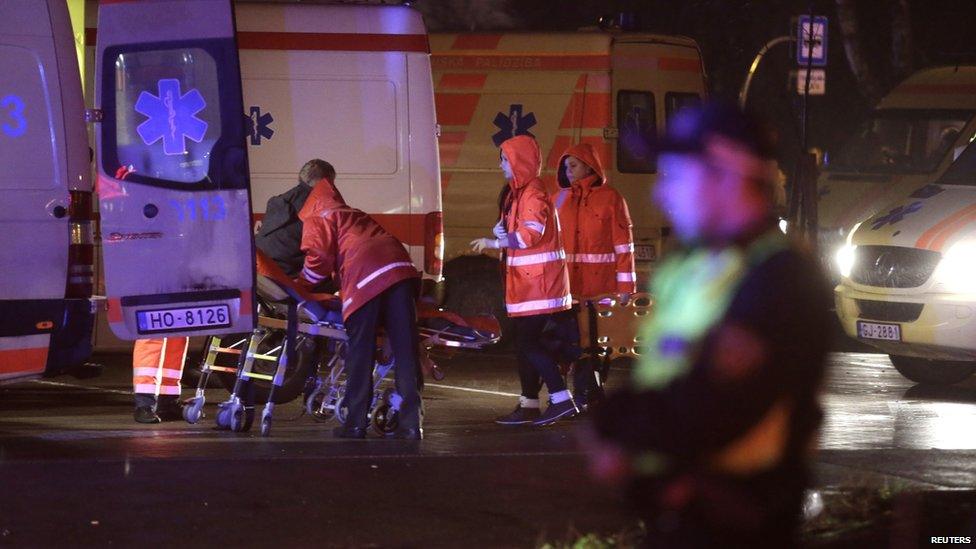 Emergency service medics take care of an injured person near a store with a collapsed roof in Riga on 21 November 2013