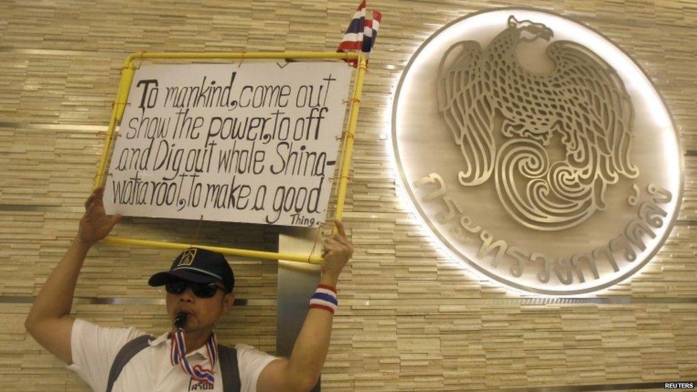 An anti-government protester blows a whistle and holds a placard during a rally at Thailand's Finance Ministry in central Bangkok, 25 November 2013