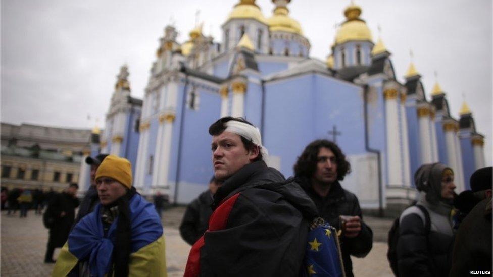 A wounded protester stands in front of St Michael's cathedral with the European Union flag in Kiev.