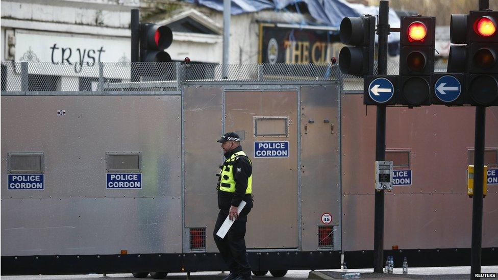 An officer walks past a police cordon set up around the site of a helicopter crash on a pub in the centre of Glasgow