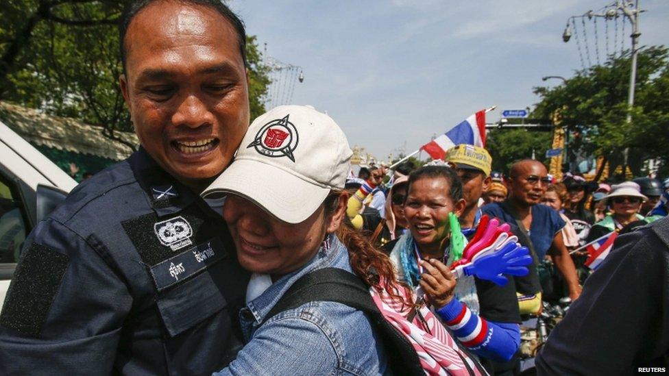 An anti-government protester hugs a riot policeman during a rally near the Government House in Bangkok, 3 December 2013