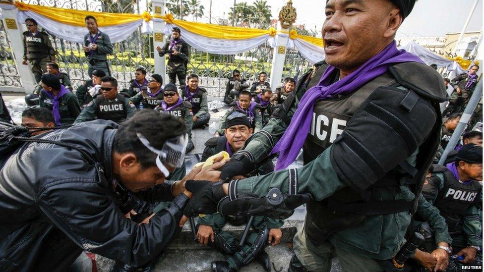 An anti-government protester shakes hands with a riot police outside the Government House during a rally in Bangkok, 3 December 2013