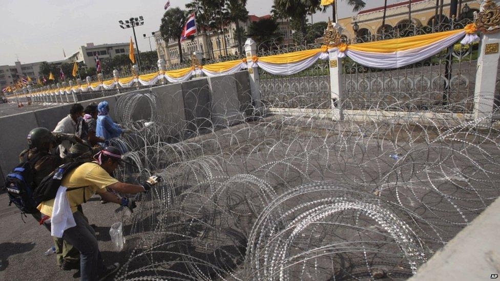 Anti-government protesters remove barbed wire outside the gates of the prime minister's office, known as Government House, in Bangkok, Thailand, 3 December 2013