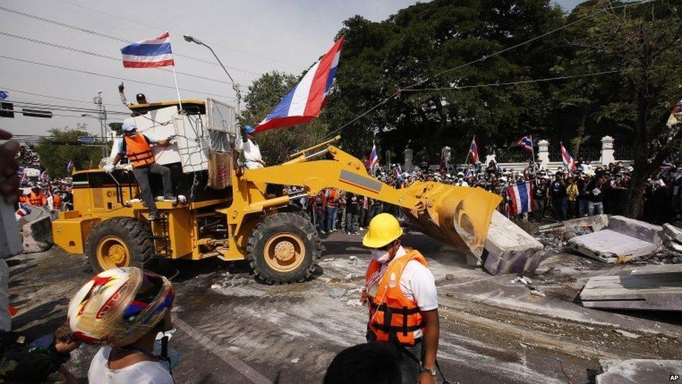 Anti-government protesters use a bulldozer to remove concrete barriers outside the city police headquarters in Bangkok, Thailand, 3 December 2013