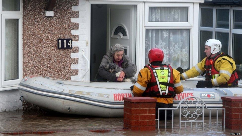 A woman and her dog led from her flooded home in Rhyl