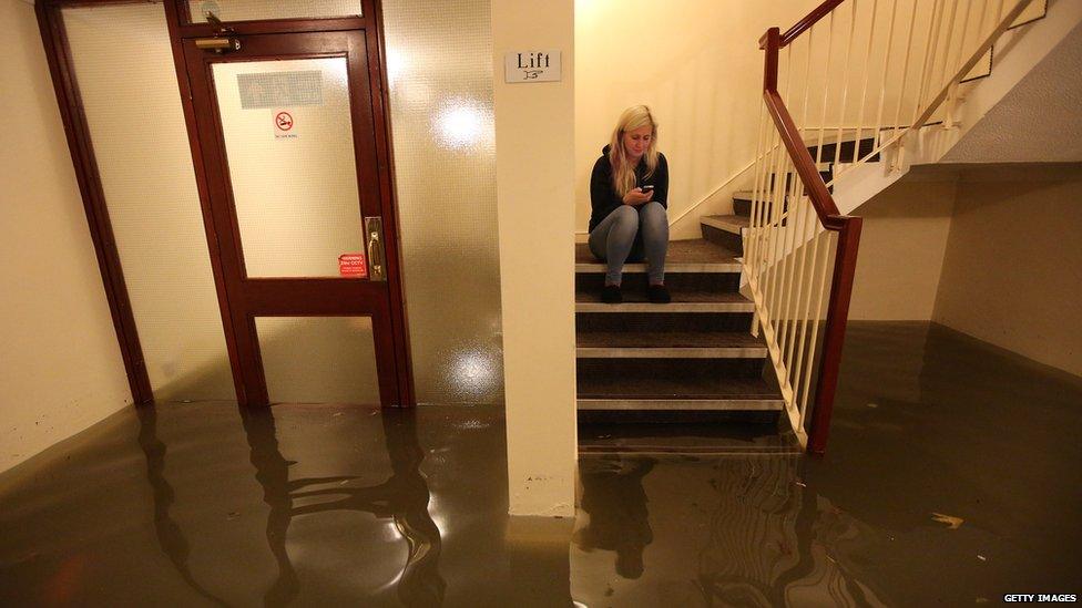 Woman sits on stairs above flood water