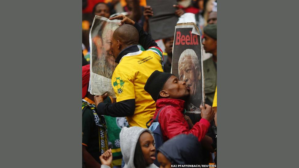 People kiss images of late former South African President Nelson Mandela