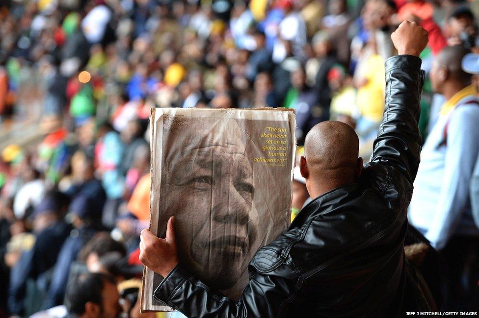 A man holds a poster of Mandela