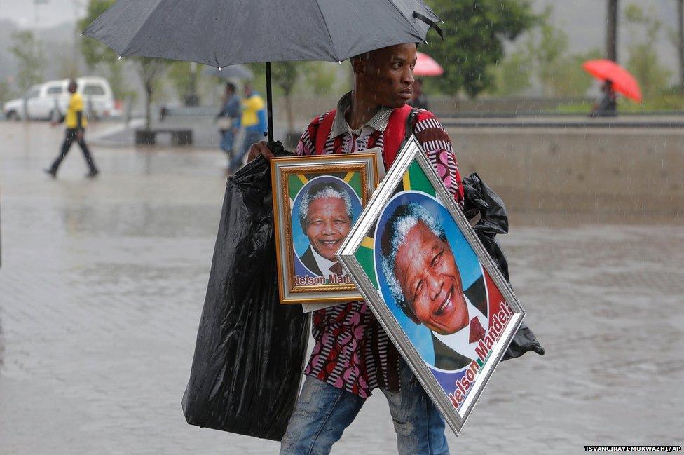 A man sells portraits of Nelson Mandela outside of the memorial service