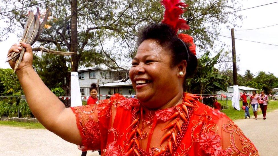 A woman carries a home made coconut bark torch today dubbed the 'Tongan torch' - during the procession of the Queen's Baton Relay in Nuku’alofa, Tonga.