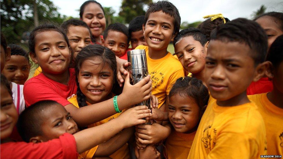 Many hands reach for Queen's Baton during the relay in Nuku’alofa, Tonga.