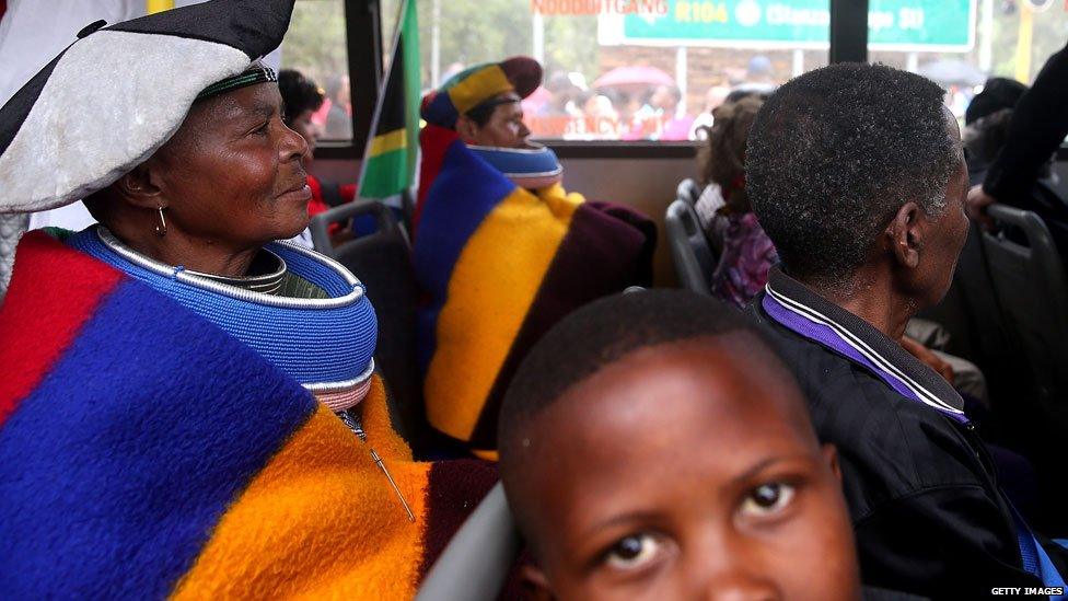 People sit on a bus that will transport them to view the body of Nelson Mandela on 11 December