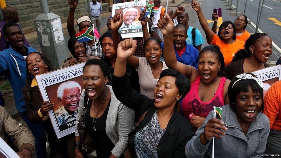 People sing and dance in the street after watching a procession carrying Nelson Mandela's coffin on 11 December