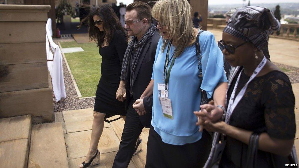 Bono and his wife Ali Hewson (L) walk with Zelda La Grange (2nd R), former assistant to Nelson Mandela, after viewing the coffin in Pretoria, 11 December