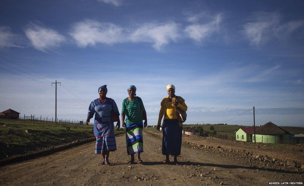 Villagers walk by foot on a dirt road to a public viewing point near the ancestral home of former South African President Nelson Mandela, to take part in his funeral ceremony in Qunu