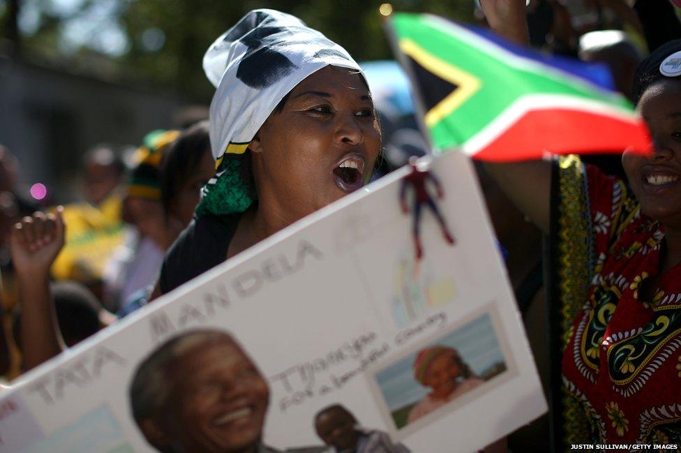 People sing and dance as they gather outside the home of former South African President Nelson Mandela