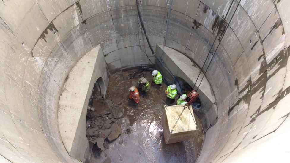 Workers in storm drain as tunnel machine breaks through