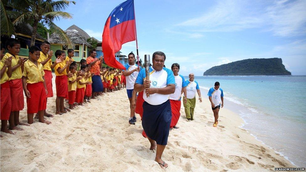 The Queen's baton touches down in Apia, Samoa and is carried down the beach by the Principal of Lalomanu primary school.