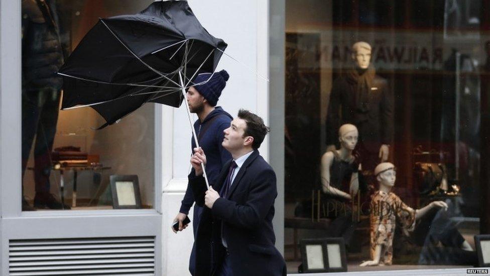 Pedestrians walk in wet and windy weather on Oxford Street in central London