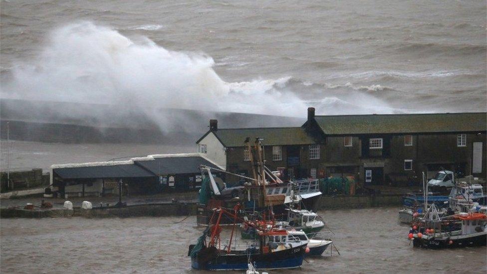 Storm waves break on the sea wall behind buildings on the Cobb in Lyme Regis