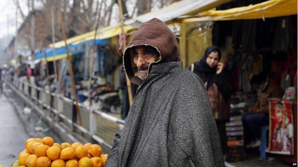 A Kashmiri street vendor, covered in woollen clothes, waits for customers in Srinagar, India, Monday, Dec. 23, 2013.