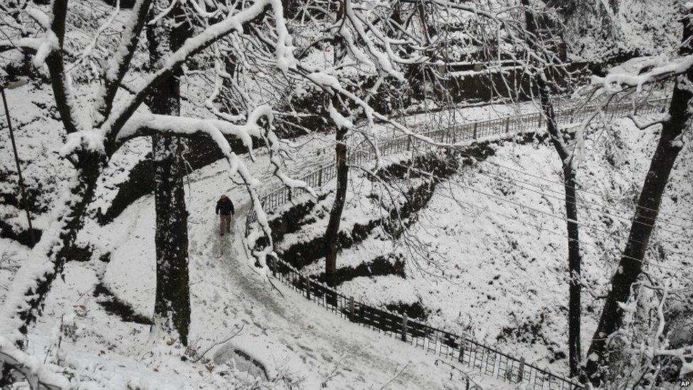 An Indian man walks on a snow-covered road after the season’s first snowfall in the northern hill town of Shimla, India, Sunday, Dec. 22, 2013.