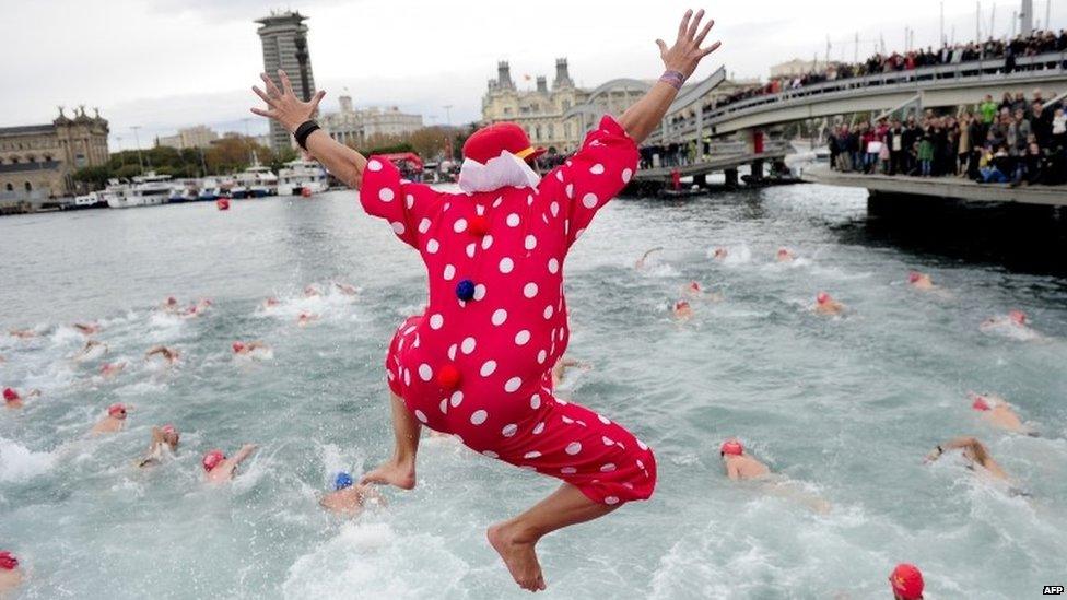 A participant in fancy dress jumps into the water during the 104th edition of the Copa Nadal (Christmas Cup) in Barcelona's Port Vell on 25 December 2013