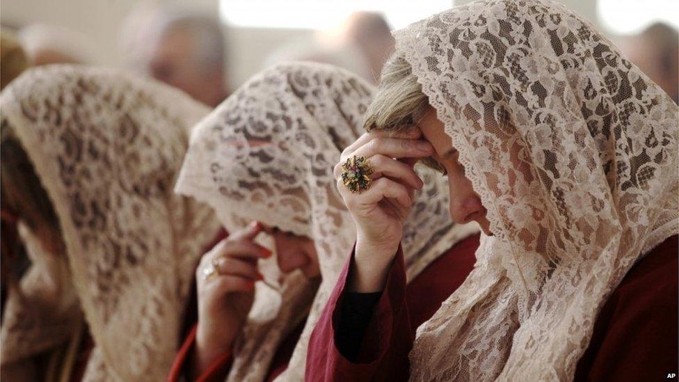 Members of St Afram's Syrian Orthodox church's choir pray during morning Christmas mass in Amman on 25 December, 2013