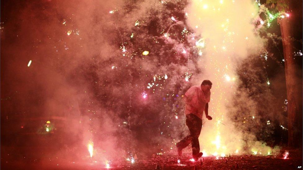 A man runs as firecrackers burst around him, on the street during the New Year celebrations in Mumbai, India, 1 January 2014