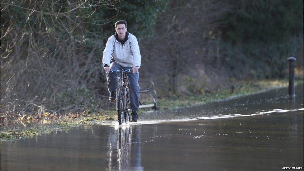 A man rides a bicycle through flood water