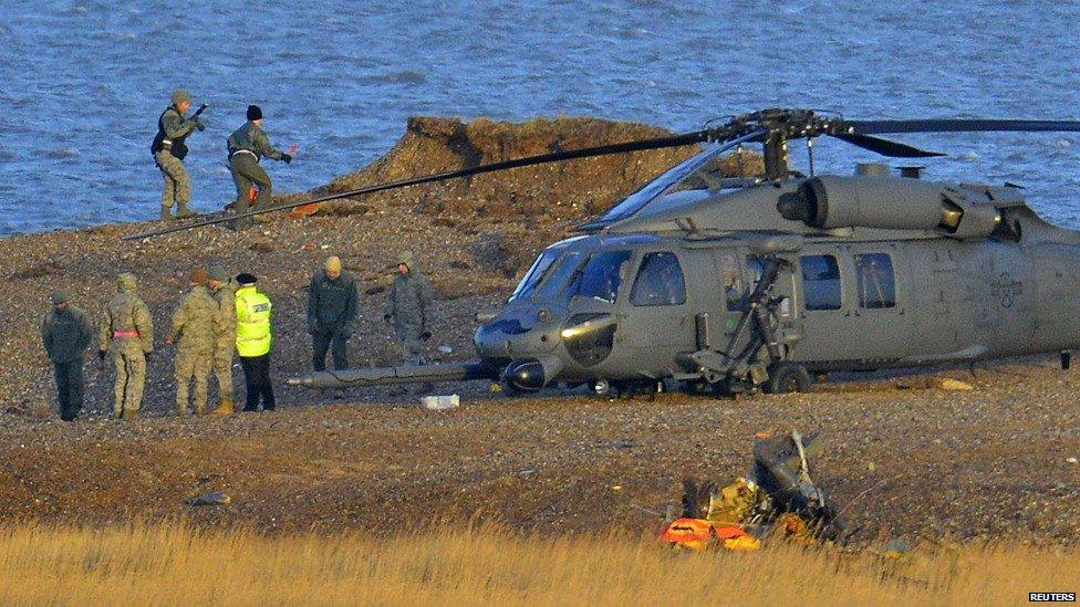 A Pave Hawk helicopter, military personnel and emergency services attend the scene of a helicopter crash on the coast near the village of Cley in Norfolk