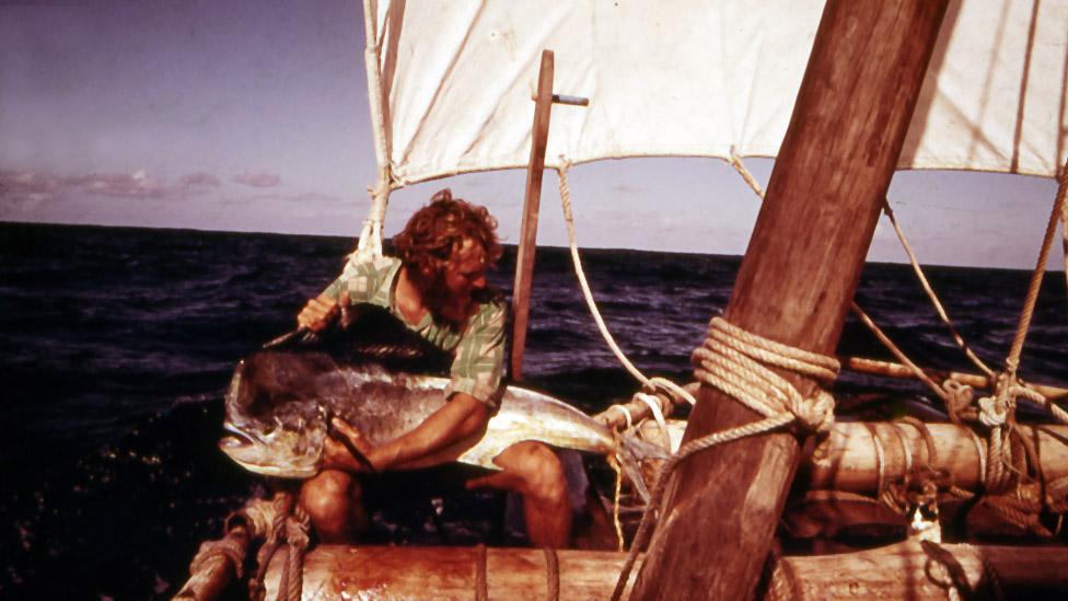 Mike Fitzgibbons holding a large fish, on the raft at sea