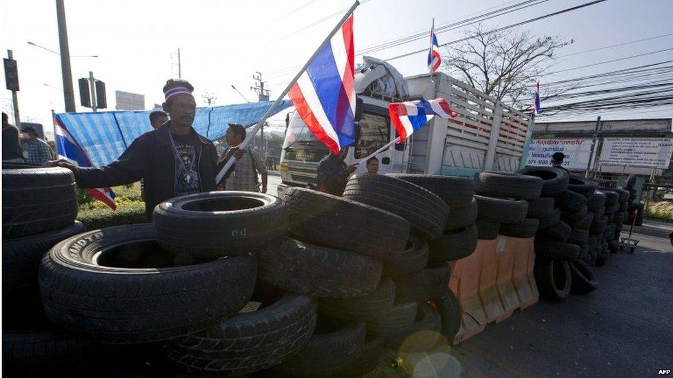 Anti-government protesters wave national flags as they block intersection during rally in Bangkok on 13 January 2014