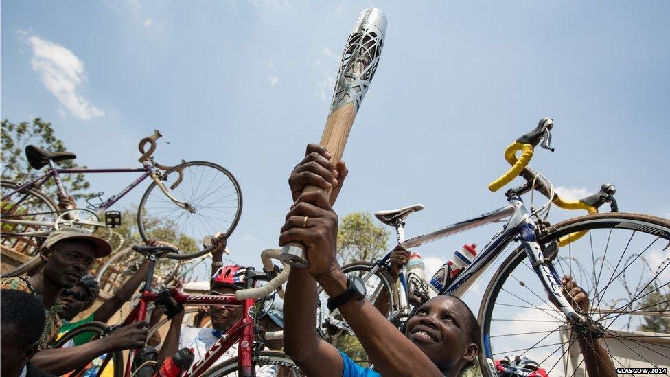 Cyclists hold the Queen's baton during the cycle to the Uganda National Olympic Committee compound in Kampala, Uganda.