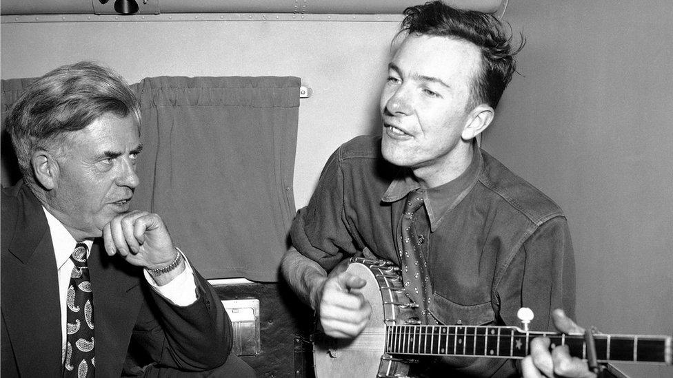 Progressive Party presidential candidate Henry A Wallace, left, listening to his banjo-playing singer Pete Seeger, on a plane in 1948