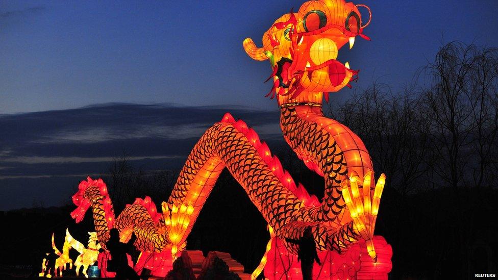 Tourists take a picture in front of a giant dragon lantern