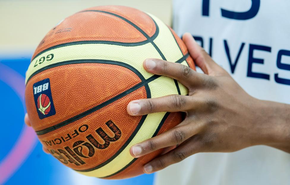 Alex Owumi holds a basketball