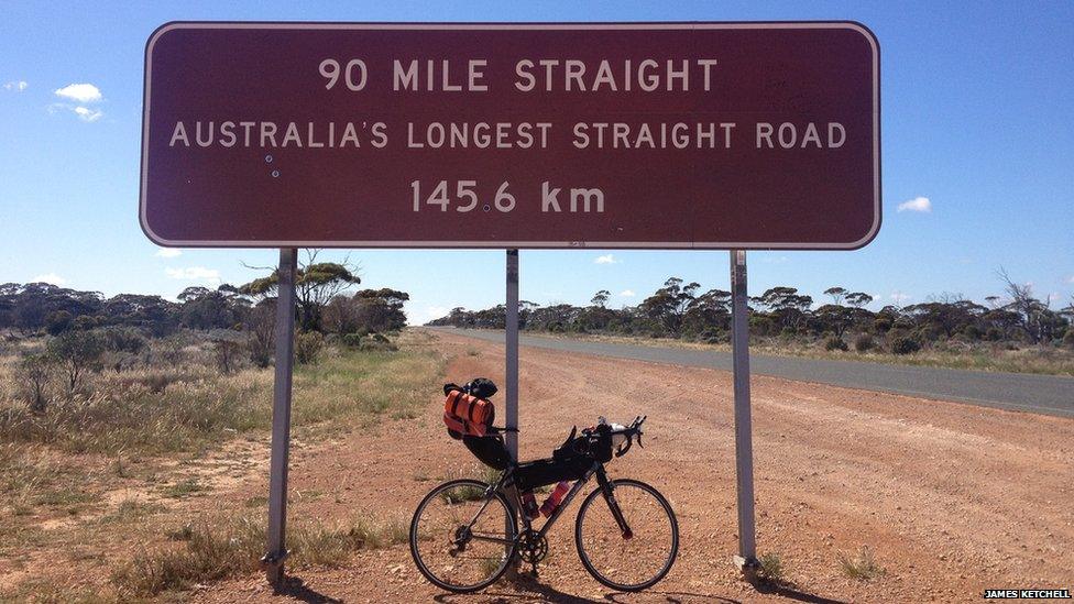 Bike propped up against a sign saying 'Australia's longest road'