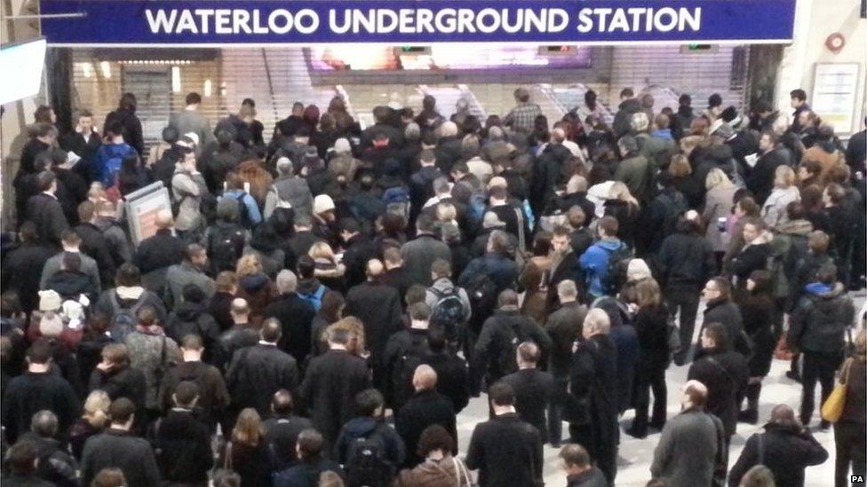 Commuters gather in front of the metal shutters at Waterloo tube station