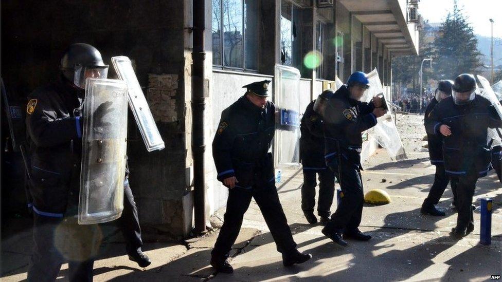 Police hold up shields outside a government building in Tuzla (7 February 2014)