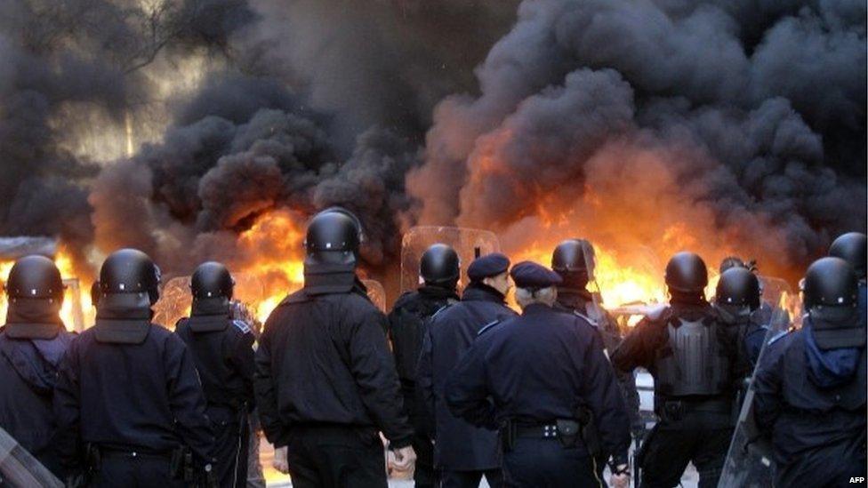 Bosnian policemen in front of a fire in Sarajevo (7 February 2014)