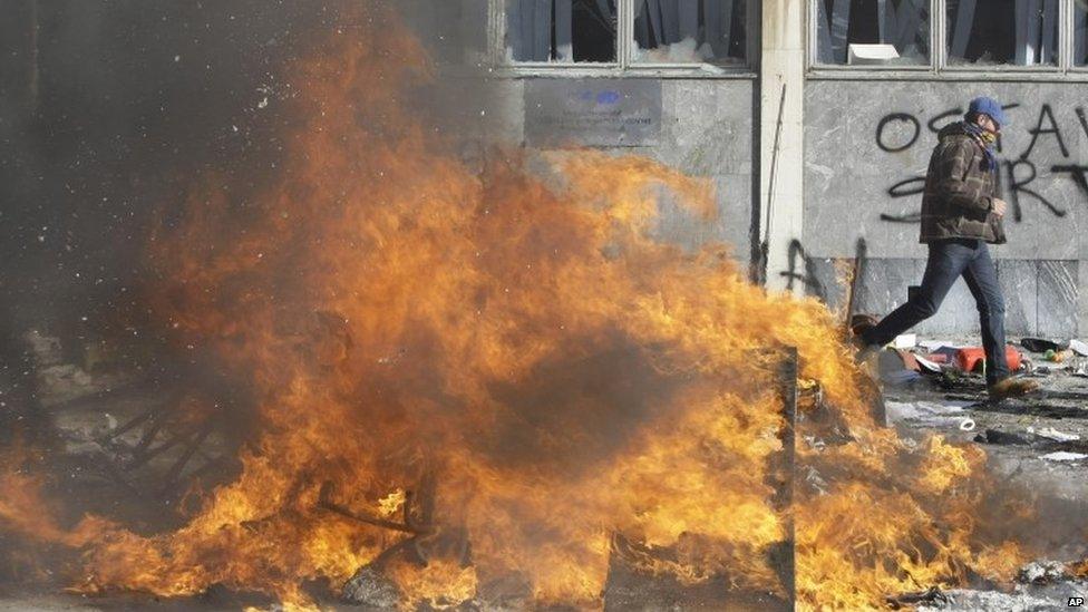 Man walks past a fire in Tuzla (7 February 2014)