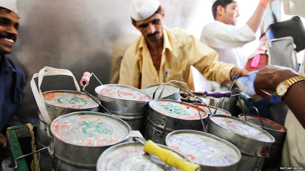 Dabbawalas, aboard a train sort their tiffin tins.