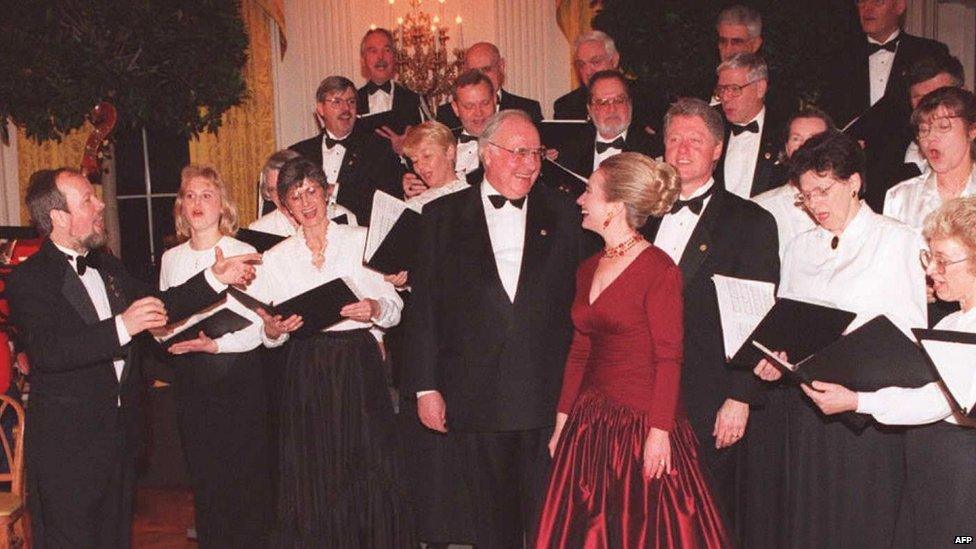 German Chancellor Helmut Kohl, President Bill Clinton, and First Lady Hillary Clinton sing with the Washington Saengerbund German chorus in 1995.